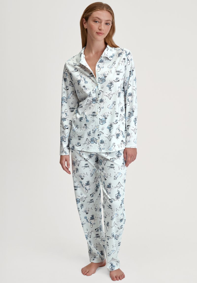 Lange mouwen pyjama set in lichtblauwe stof met een speels patroon van dieren en voorwerpen. Geknoopte shirt en rechte pijpen.
