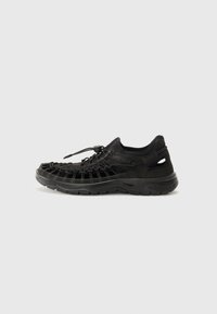 Czarne sportowe buty z plecioną cholewką i gumową podeszwą, z regulowanym sznurowaniem, otworami wentylacyjnymi i teksturowanym wykończeniem.