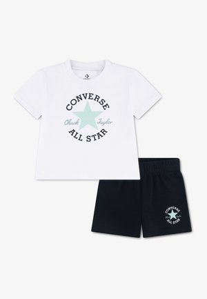 Camiseta blanca de manga corta con estrella azul claro y texto "Converse All Star" combinada con pantalones cortos negros que presentan el mismo logo en la pierna.