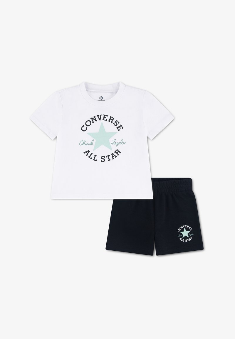 Chemise blanche à manches courtes avec une étoile bleu clair et le texte « Converse All Star », associée à un short noir avec un logo assorti sur la jambe.