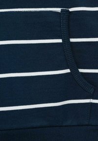 Námořnická modrá bavlněná tkanina s bílými horizontálními pruhy. Obsahuje kapsu s žebrovanou texturou a elastickým pasem.