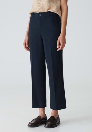 Pantalons taillés bleu marine avec taille haute, devant plat et jambes larges. Fabriqués en tissu lisse, avec fermeture à bouton sur le devant et poches au dos.