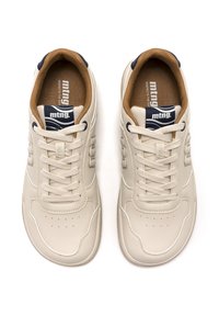 Zapatillas beige de cuero con puntera redondeada, suelas texturizadas y detalles de costuras blancas. Los cordones son gris claro, con un acento azul marino en la lengüeta.