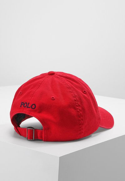 Piros pamut baseballsapka állítható pánttal a hátsó részen, kék "POLO" hímzéssel a záródás közelében. Sima textúrájú.