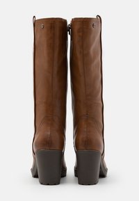 Bottes montantes en cuir marron avec une texture lisse, bout carré et talons carrés. Caractéristiques : coutures subtiles et fermeture éclair à l'arrière.