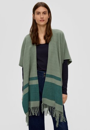 Lichtgroene sjaal met een zachte textuur, voorzien van teal strepen en franjes aan de onderkant, gedragen over een donkere top en jeans.