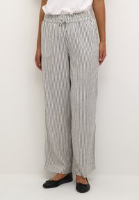 Striped linen blend pants in white and navy, featuring a drawstring waistband, wide legs, and two front pockets.