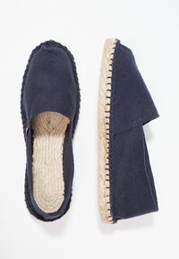 Marineblaue Espadrilles aus Stoff mit gewebten Jute-Sohlen, runden Zehen und genähten Details entlang der Kanten. Weiche, strukturierte Oberfläche.