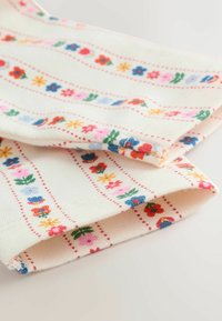 Pamut anyag, amelyen krémszínű háttér található, piros, kék, rózsaszín és sárga virágmintával, keskeny piros csíkokkal elválasztva.