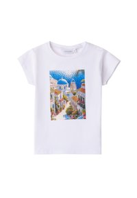 Camiseta blanca de algodón con un gráfico colorido de un paisaje mediterráneo que incluye cúpulas azules, edificios y acentos florales.