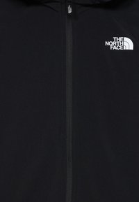Svart hettegenser med glidelås, laget av lettvektsmateriell. The North Face-logoen vises øverst til venstre i hvitt.