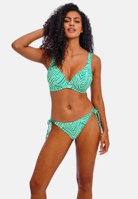 Ensemble de bikini vert avec un motif en zigzag. Le haut présente un décolleté plongeant et des bretelles réglables ; le bas possède des liens sur les côtés. Texture lisse.