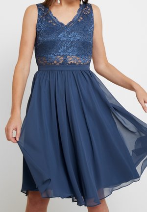 Ciemnoniebieska sukienka z koronkowym gorsetem, bez rękawów i z lejącym się spódnicą z szyfonu. Talia jest marszczona, tworząc delikatną sylwetkę.