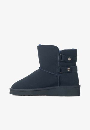 Navyblaue Wildleder-Ankelboots mit doppelten Schnallenriemen, Schafwollbesatz, abgerundeter Zehenform und strukturiertem Sohle für Rutschfestigkeit.