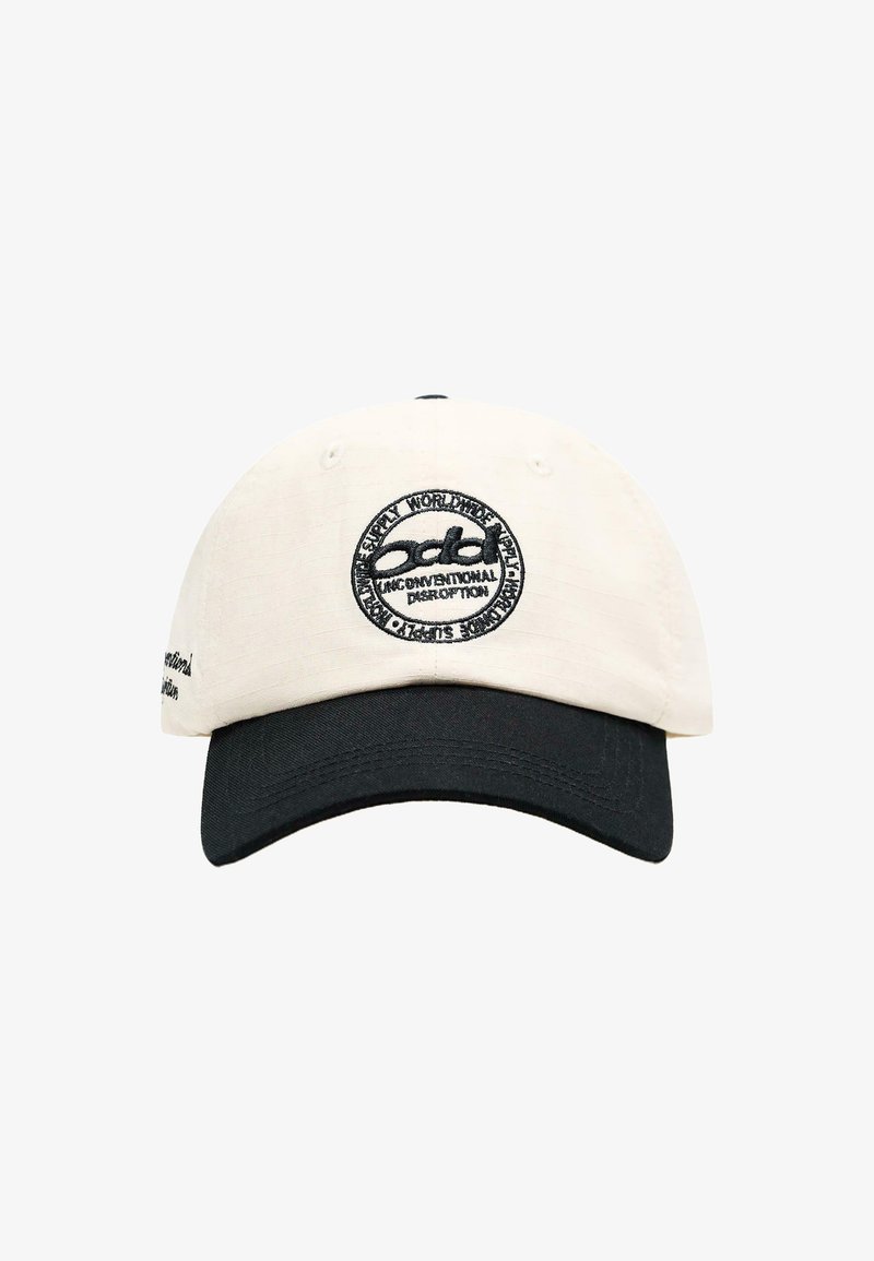 Witte en zwarte honkbalpet met een cirkelvormig zwart geborduurd logo en tekst op het voorpaneel.