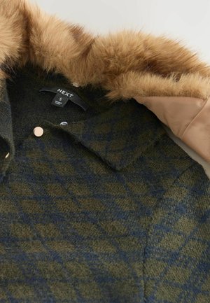 Vihreä ja laivastonsininen ruudullinen villakangastakki tekoturkiskauluksella, beige vuori ja pyöreät metallinapit. Tuotetunnistus lukee "NEXT", koko S.
