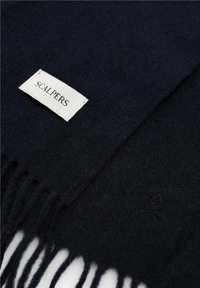 Bufanda de un azul marino oscuro, hecha de un tejido suave, con flecos en los bordes y una etiqueta blanca con el texto "SCALPERS", además de un detalle de logotipo sutil.
