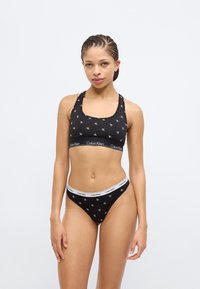 Μαύρο αθλητικό σουτιέν από βαμβάκι και ταιριαστό στρινγκ, με επαναλαμβανόμενο μοτίβο λογότυπου, ελαστική μέση με το όνομα της μάρκας και λεία υφή.