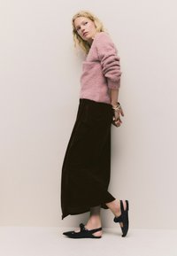 Rožinė pūkuota megztinis, juoda veliūrinė maksi sijonas ir juodi slingback batai su kaspinėlio detalėmis. Pabrėžiami švelnūs audiniai ir kontrastingos spalvos.