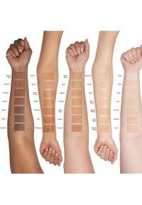 Four arms with varying skin tones display rows of foundation swatches, arranged from deep to light shades, with clear labeling of each color.