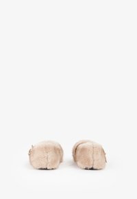 Pantofole beige pelose con forma arrotondata, realizzate in morbido materiale di pelliccia e con piccoli cinturini posteriori per una vestibilità sicura. Suole piatte.