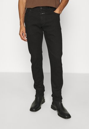 Mustat slim-fit farkut, joissa on hienovarainen haalistuminen, viisi taskua, etupainike ja sileä, jäsennelty pinta. Yhdistetty mustiin nilkkasaappaisiin.