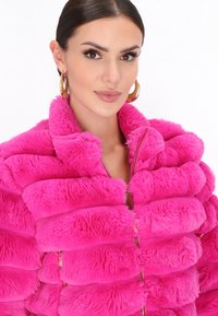 Faux fur pink jakke med en puffy, quiltet design og lynlås lukning. Har en høj krave og en glat, blød tekstur. Guld hardware detaljer.