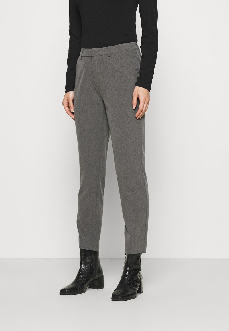 Pantalon gris sur mesure avec un tissu texturé, doté de poches latérales et d'une coupe slim. Associé à des bottines noires brillantes.
