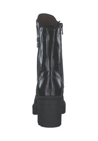 Bottine noire en vernis avec un talon épais, dotée d'une fermeture éclair latérale et d'une texture lisse et brillante. Design simple sans accents supplémentaires.