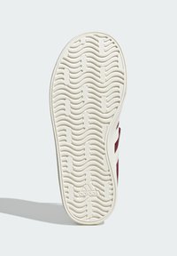 Bijela gumena potplata s valovitom teksturom, s utisnutim logotipom. Vidljivi crveni tekstilni bočni detalji.