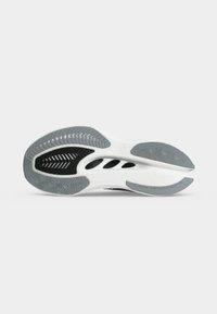 Εξωτερική σόλα αθλητικού παπουτσιού με γκρι και μαύρο ελαστικό πέλμα και λευκό ενδιάμεσο πέλμα, που δείχνει οπές αερισμού και καμπυλωτό σχέδιο.