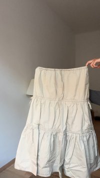 Jupe en coton beige avec trois volants froncés, taille élastique et coutures apparentes. Texture légère, design décontracté.