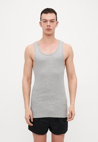 Gray sleeveless tank top made of ribbed fabric with a round neckline and raw edges, paired with black shorts.