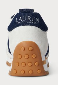 Bílé a námořnické tenisky s semišovým povrchem, které mají gumovou podrážku s texturovaným gripem a na patě logo "LAUREN RALPH LAUREN".