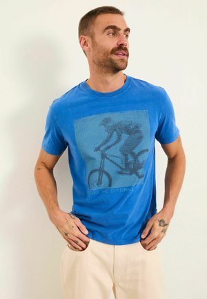 Blaues Baumwoll-T-Shirt mit einer Grafik eines Radfahrers in dunklen Punkten, darunter der Text "Bremsen sind optional". Kurzärmlig mit rundem Ausschnitt.