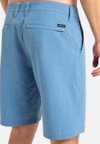 Bermudas de color azul claro fabricadas con una tela suave, con dos bolsillos traseros, una etiqueta en la cintura y un diseño de pierna recta.