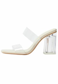 Sandale s prozirnim petama koje imaju prozirne trake, bež podstavu i debelu prozirnu blok-petu. Elegantna i glatka forma s minimalističkim estetskim izgledom.