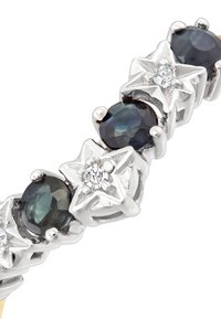 Sudraba zvaigžņu formas rokassprādze ar tumši ziliem ovāla akmeņiem un caurspīdīgu dimantu akcentu, demonstrējot pulētu apdari un sarežģītu dizainu.