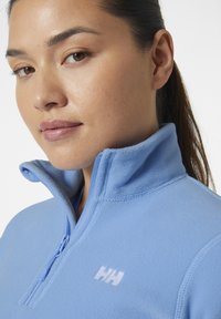 Jasnoniebieski polarowy półgolf z zamkiem błyskawicznym na ćwierć, haftowanym logo na klatce piersiowej. Miękka struktura, dopasowany krój.