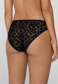 Braguitas hipster negras transparentes con un patrón de encaje floral, material de nailon, cinturilla elástica y un acabado suave en los bordes.