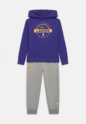 Lila hoodie med "LAKERS"-logotyp i gult, kombinerad med gråa sweatpants med orange detaljer och NBA-logotyp på benet.