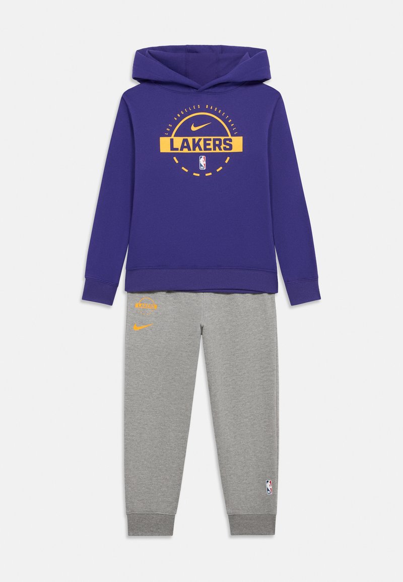 Lilla hættetrøje med "LAKERS" logo i gul, parret med grå sweatpants med orange accenter og NBA logo patch på benet.
