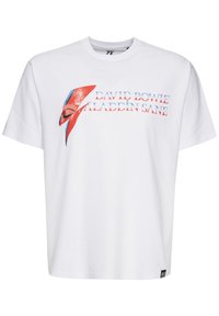 Hvid bomulds T-shirt med et grafisk print af et rødt og blåt lyn, teksten lyder "DAVID BOWIE" og "ALADDIN SANE" nedenfor.