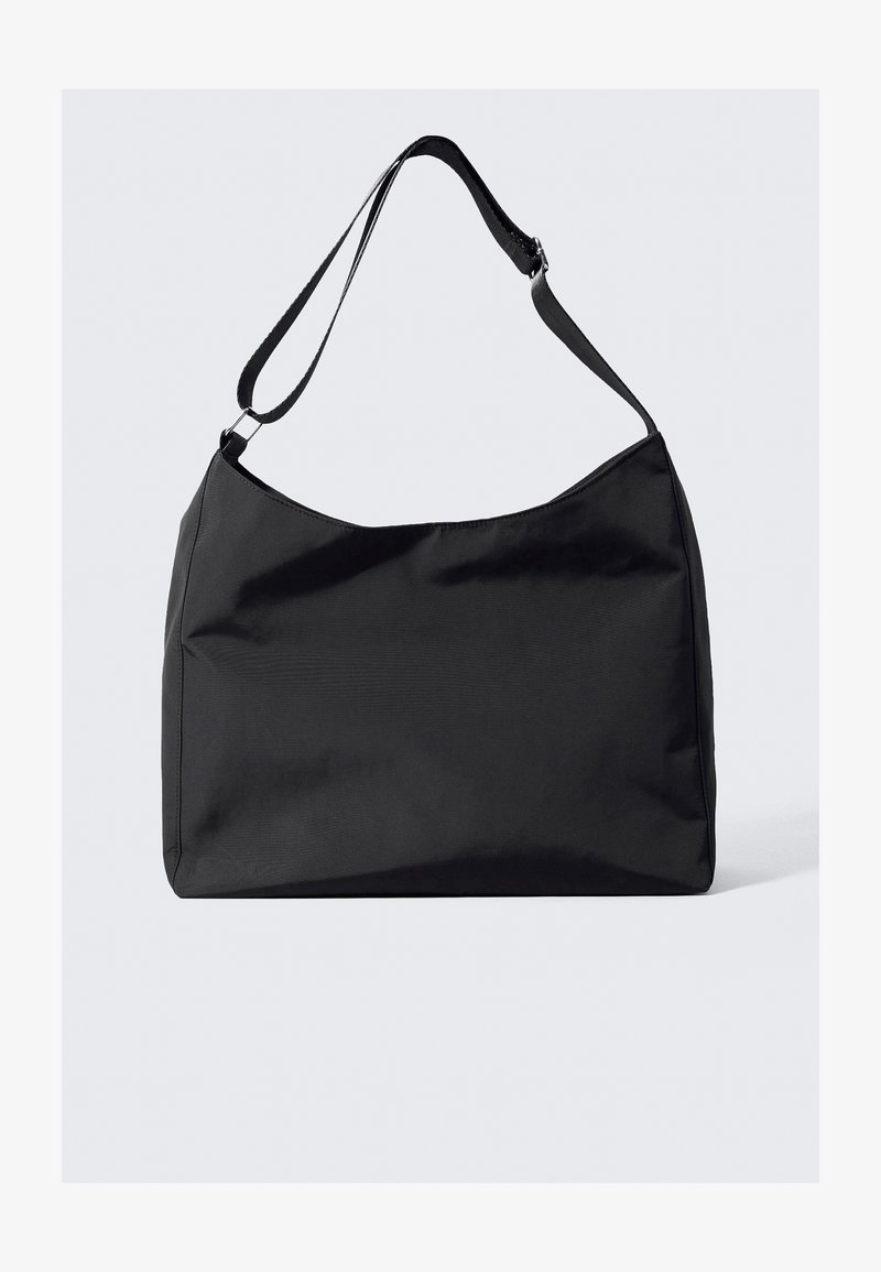 Bolsa de ombro em tecido preto com uma textura suave, parte superior curvada e uma única alça ajustável. Apresenta um design minimalista e sem acessórios visíveis.
