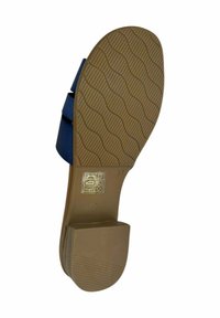 Sandalia azul con tacón plano, suela de goma con un patrón ondulado y detalle de talla en relieve. Textura suave y diseño minimalista.