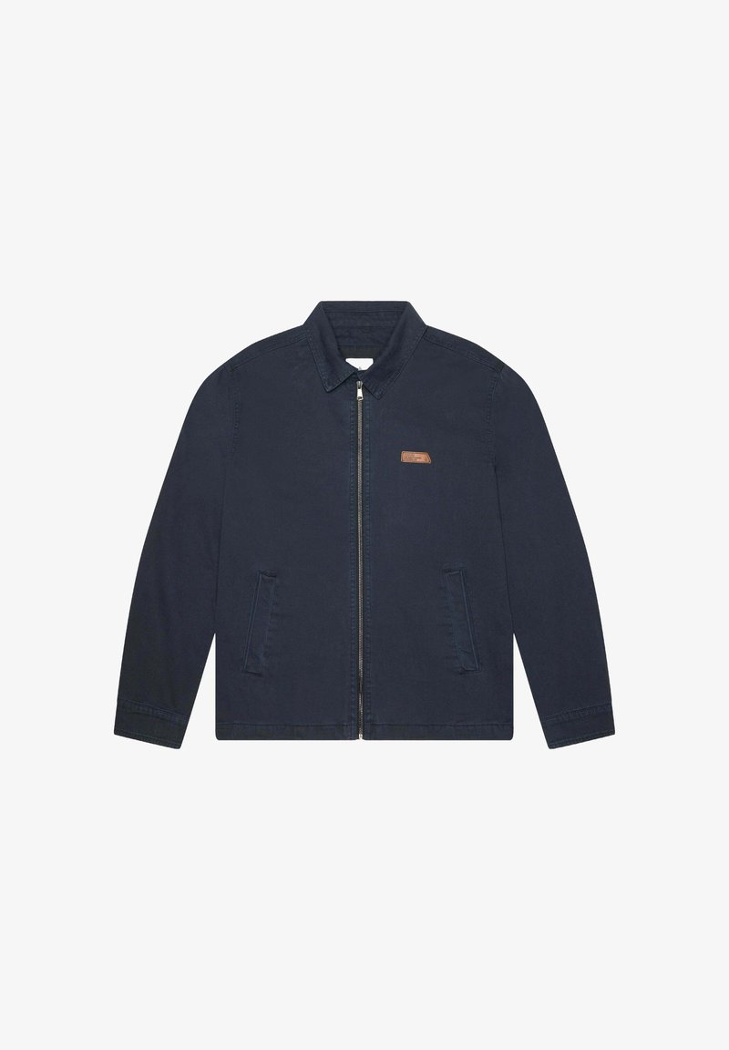 Veste en coton bleu marine avec un col pointu, fermeture éclair à l'avant et deux poches latérales ; présente un petit accent en cuir marron avec un logo.