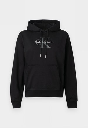Sort Calvin Klein-hoodie med lynlås foran, snøre i hætten og hvidt og gråt logo trykt på brystet.