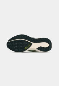 Sort gummisål med tekstureret grebsmønster, lys grå mellemsål med "NIKE STORM-TREAD" i grøn. Buet hældesign.