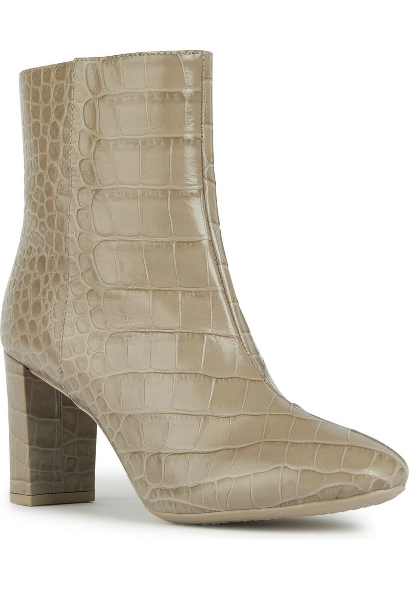 Beige Knöchelstiefel mit Krokodilstruktur, spitz zulaufender Zehenpartie und Blockabsatz. Hergestellt aus glänzendem synthetischem Material, mit einer glatten Oberfläche.