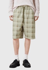 Grønne ternede shorts med elastisk talje og snor, lavet af letvægtsstof. Knælængde med en afslappet pasform.